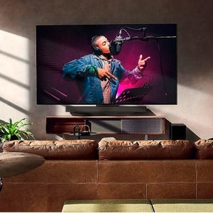 Mounted flat-screen TV, soundbar, and leather sofa in a living room.