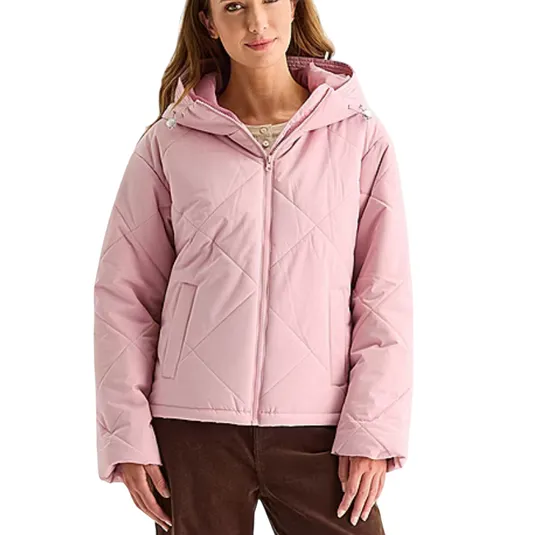 A woman wearing a light pink quilted hooded jacket with front pockets and a front zipper, paired with brown pants.