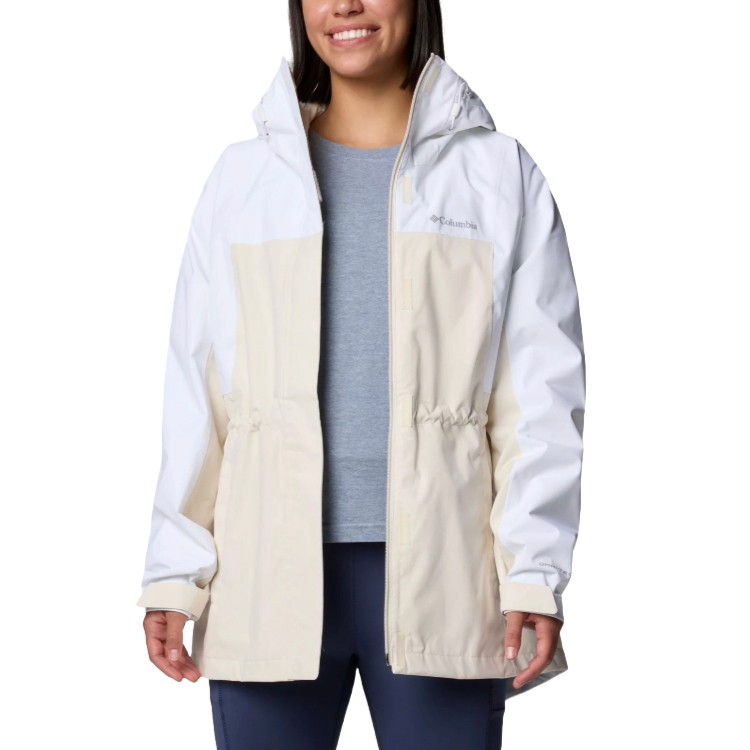 A woman is wearing a Columbia two-tone jacket in white and beige with a hood, over a gray shirt and dark pants.