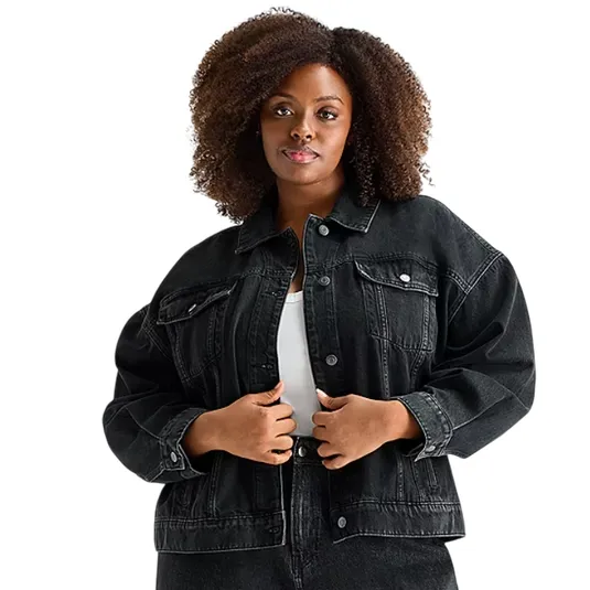A person wearing a black denim jacket over a white top, paired with black denim jeans.