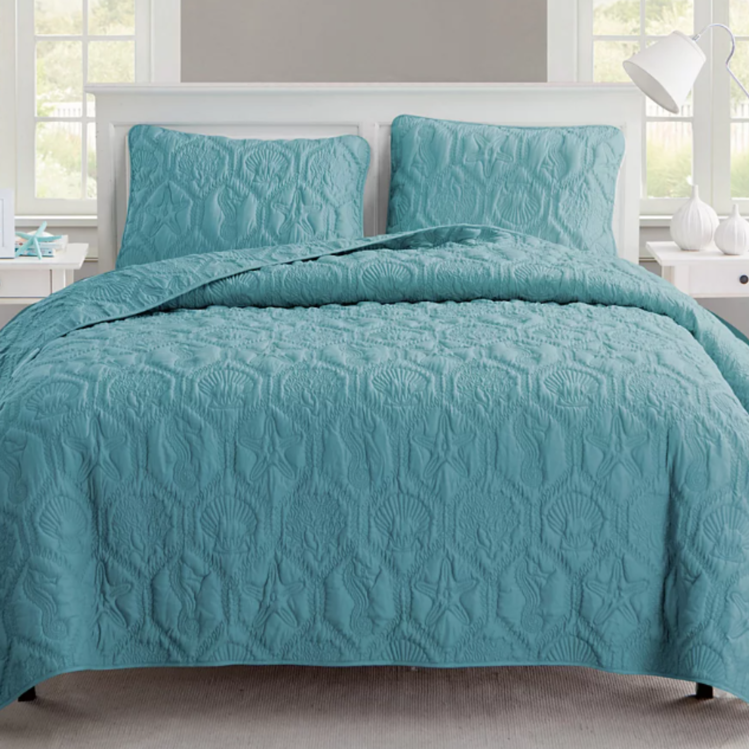 A turquoise quilted bedspread set with matching pillow shams featuring a sea-life pattern.