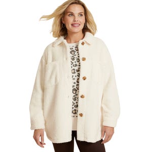 A woman wears a cream-colored sherpa jacket with large buttons and dual chest pockets over a leopard print top, paired with dark pants. The jacket has a casual, cozy look suitable for cooler weather.