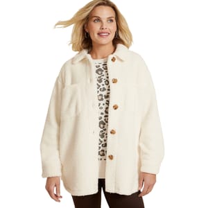 A woman wears a cream-colored sherpa jacket with large buttons and dual chest pockets over a leopard print top, paired with dark pants. The jacket has a casual, cozy look suitable for cooler weather.