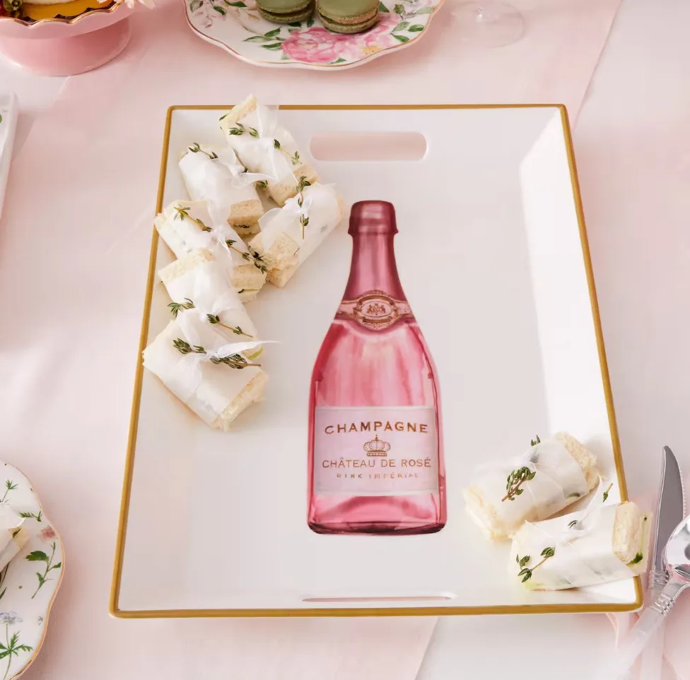 A serving tray with a depiction of a pink champagne bottle, surrounded by wrapped sandwiches.