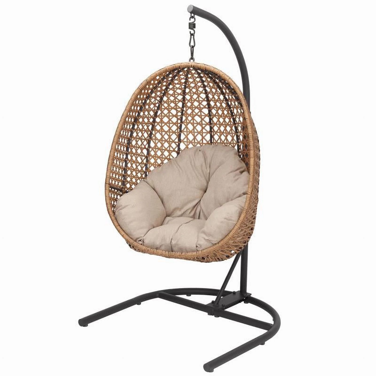 A hanging egg chair with a woven rattan design, featuring a cushioned interior for comfort. It is supported by a sturdy black metal stand with a curved base and hook for secure hanging.