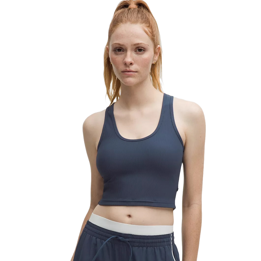 A woman in a dark blue ribbed crop tank top with scoop neckline and matching drawstring shorts, featuring a white waistband.