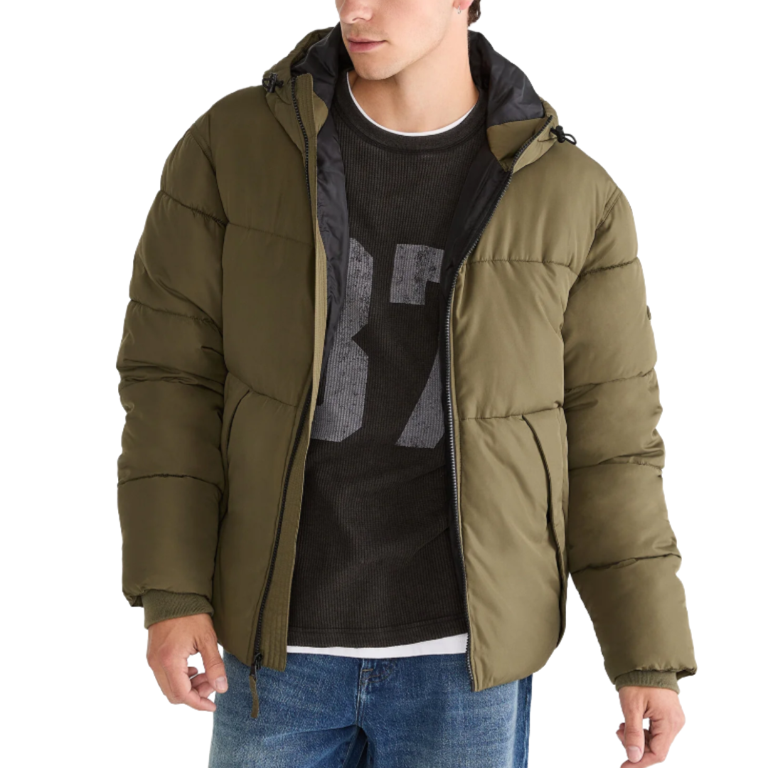 A person is wearing a green puffer jacket with a hood, paired with a black sweater featuring the number \“87,\“ and blue jeans.