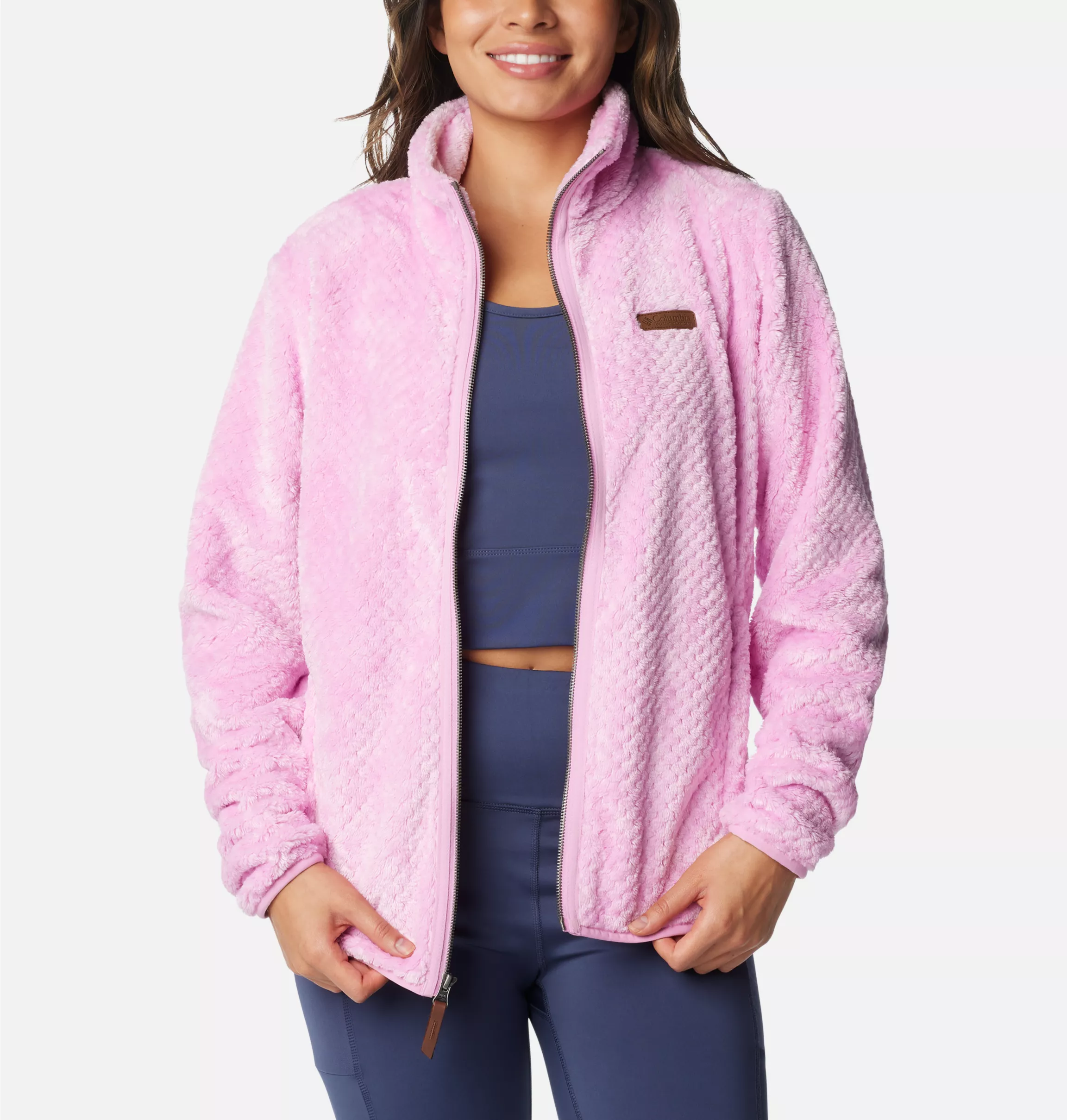 Woman in a pink fleece jacket with a high collar and navy blue athletic leggings.