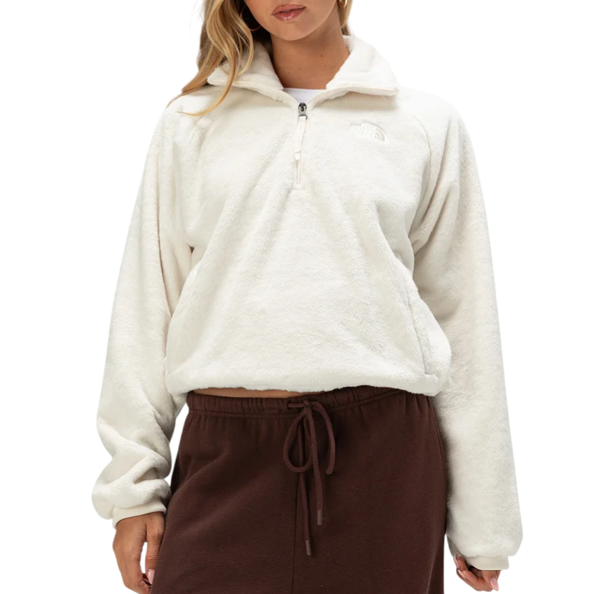 A woman is wearing a white, plush half-zip fleece pullover paired with dark brown drawstring pants.