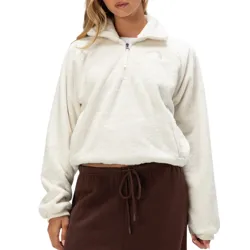 A woman is wearing a white, plush half-zip fleece pullover paired with dark brown drawstring pants.