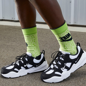 A person is wearing black and white sneakers with neon green socks.