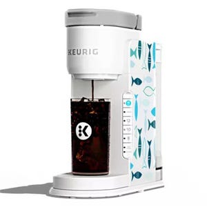 A Keurig coffee maker with a fish pattern design brews coffee into a cup.