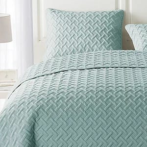 Light blue bedspread set with a textured, geometric pattern, including matching pillow shams.