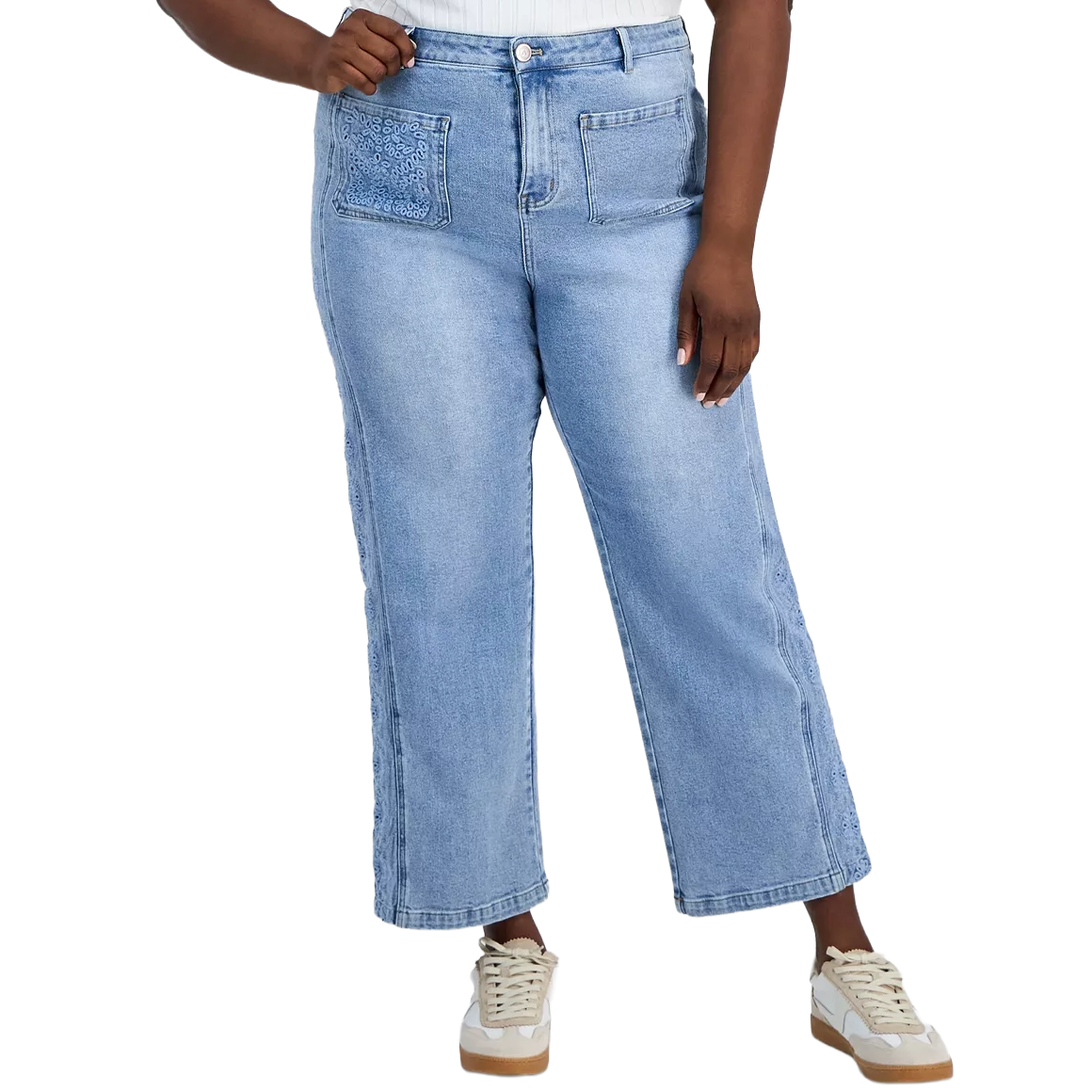 Light blue plus-size denim jeans with wide legs, front pockets, and crochet detailing paired with white sneakers.