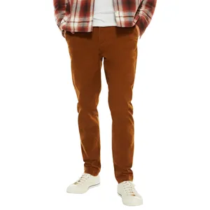 A person is wearing rust-colored skinny jeans, white sneakers, a white shirt, and a red plaid flannel shirt.