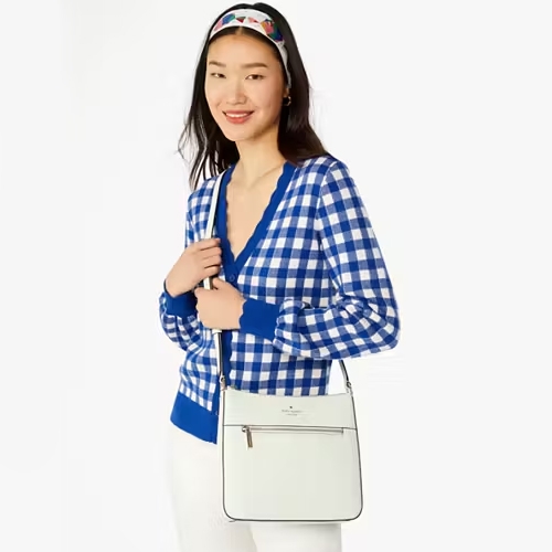 A woman wearing a blue and white checked cardigan, a headband, and holding a white shoulder bag.