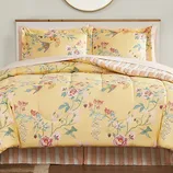 Yellow floral-patterned comforter set with matching pillow shams, featuring a reversible striped design.