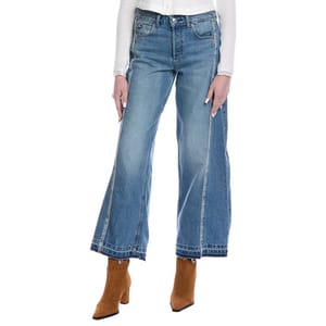 A person is wearing wide-leg blue jeans paired with tan ankle boots and a white long-sleeve top.