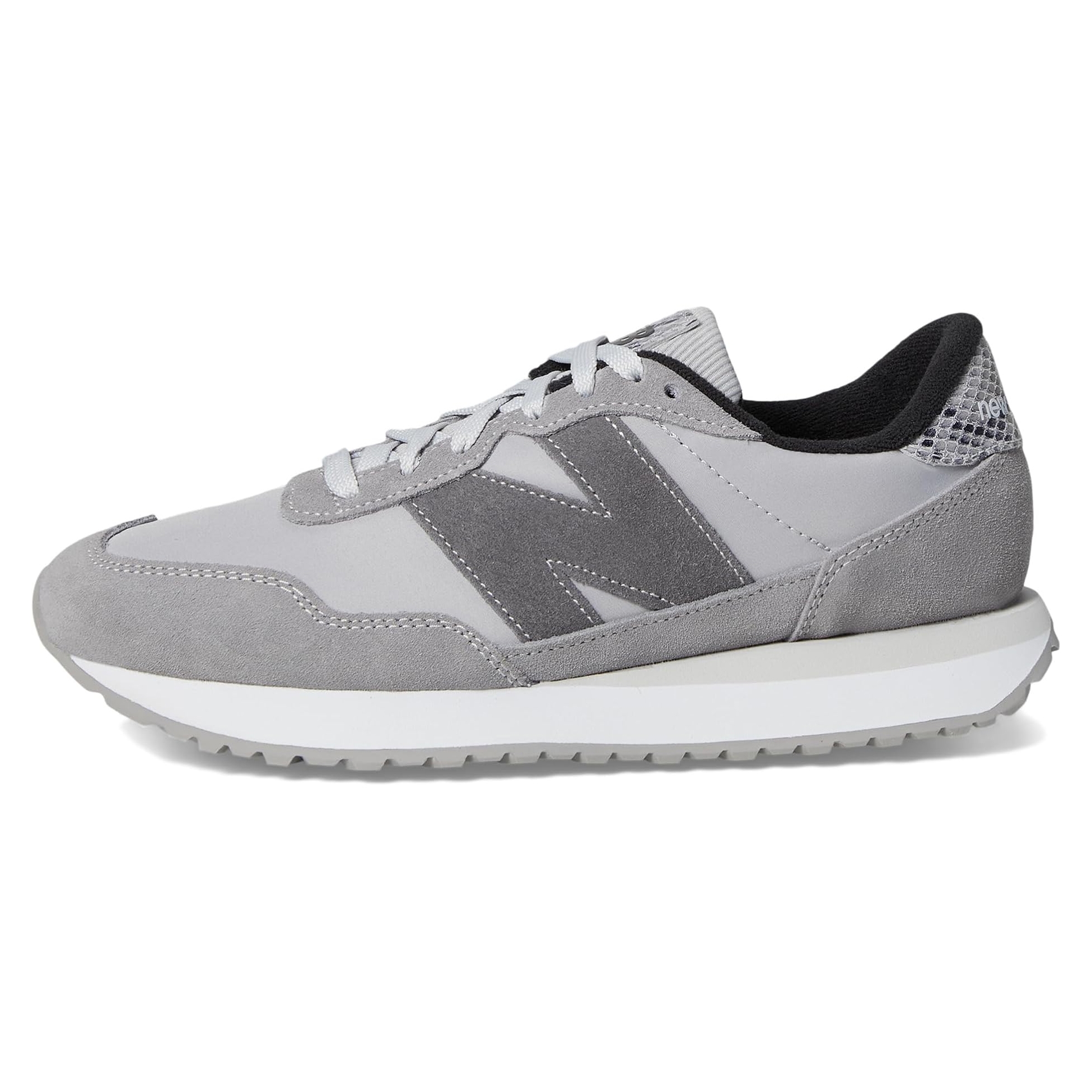 A gray sneaker featuring suede and mesh materials with a prominent \“N\“ logo on the side, and a white midsole with a textured gray outsole.