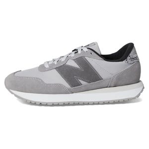 A gray sneaker featuring suede and mesh materials with a prominent \“N\“ logo on the side, and a white midsole with a textured gray outsole.