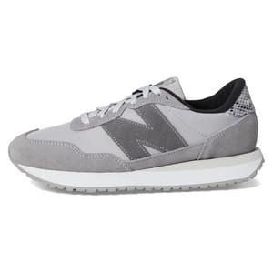 A gray sneaker featuring suede and mesh materials with a prominent \“N\“ logo on the side, and a white midsole with a textured gray outsole.