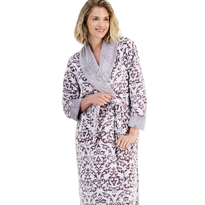 A woman wearing a patterned bathrobe with a plush shawl collar and tie belt, featuring a purple and gray floral design.
