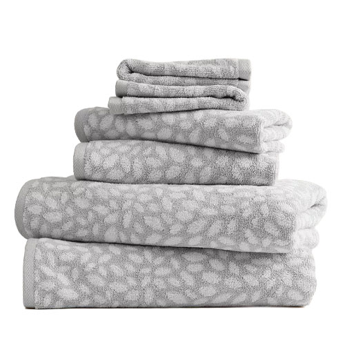 A stack of grey towels with a white floral pattern, including bath towels, hand towels, and washcloths.