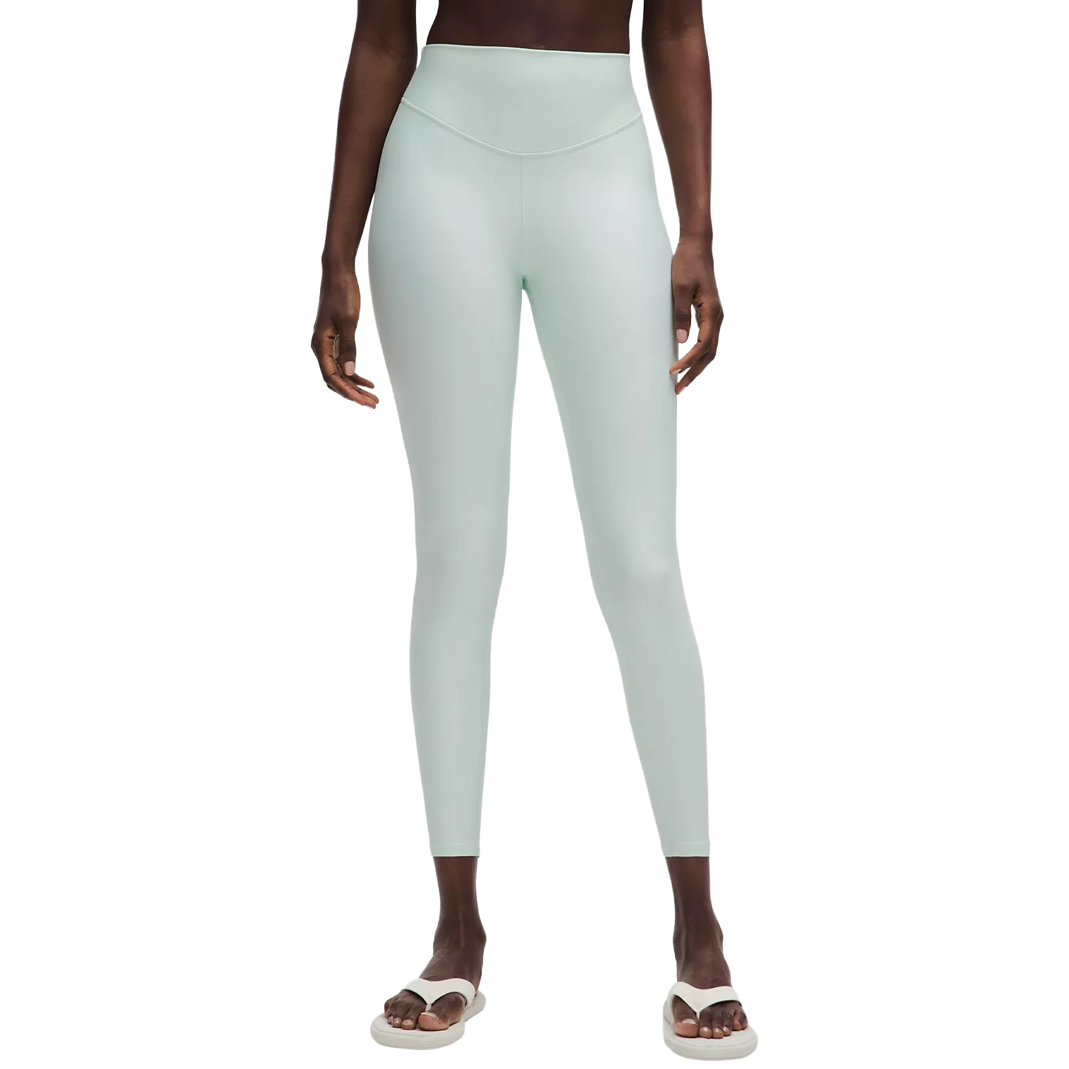 A person wearing light mint green high-waisted leggings and white sandals.