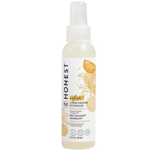 A bottle of Honest Conditioning Detangler with a spray nozzle, featuring a citrus vanilla scent, in a 4 fl oz size. The label displays yellow citrus fruit illustrations.