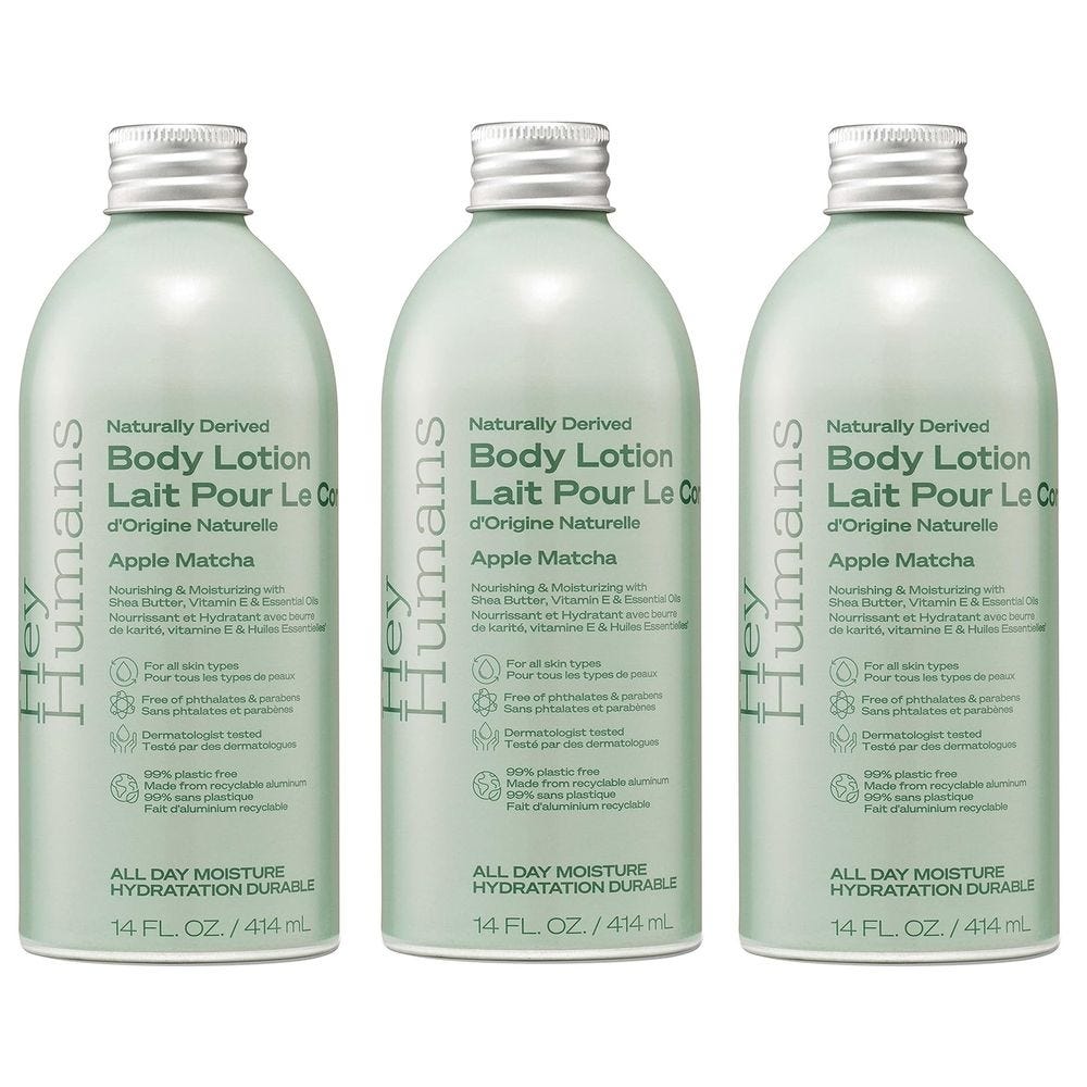 Three bottles of Hey Humans Apple Matcha Body Lotion, 14 fl. oz. each, are displayed. The lotion is naturally derived, suitable for all skin types, and free of phthalates and parabens. Made from recyclable aluminum.