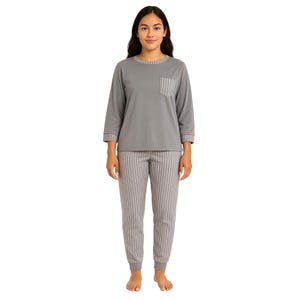 A woman is wearing a grey pajama set with a long-sleeve top featuring a pocket and striped collar and cuffs, paired with matching striped pants.