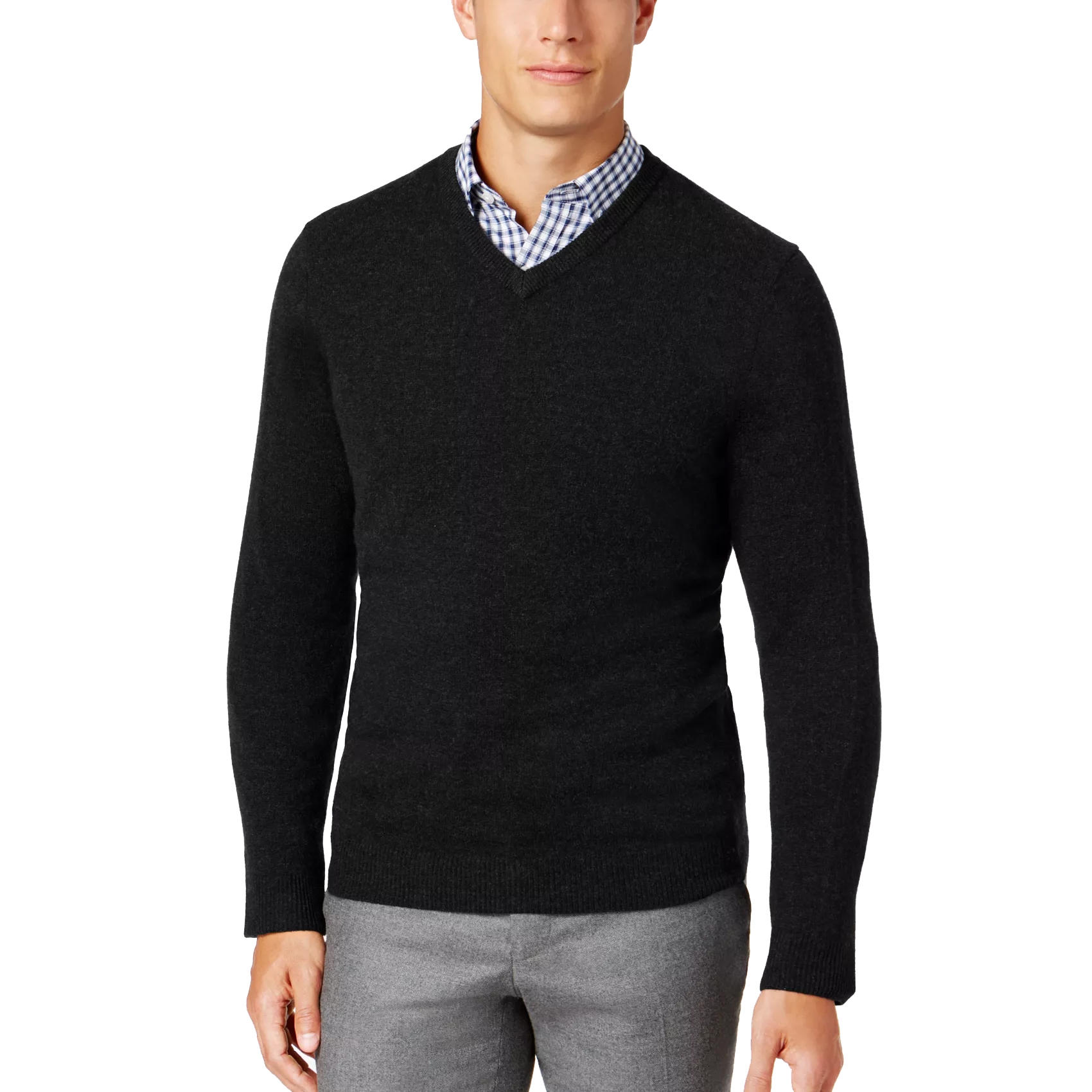 A man is wearing a black V-neck sweater over a blue and white checkered shirt, paired with gray pants.