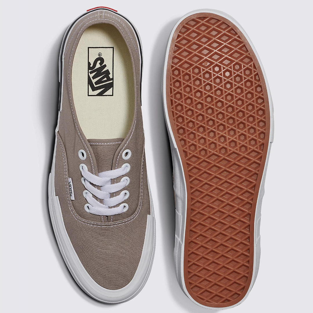 A pair of canvas low-top sneakers with white laces and a brown waffle-patterned sole.