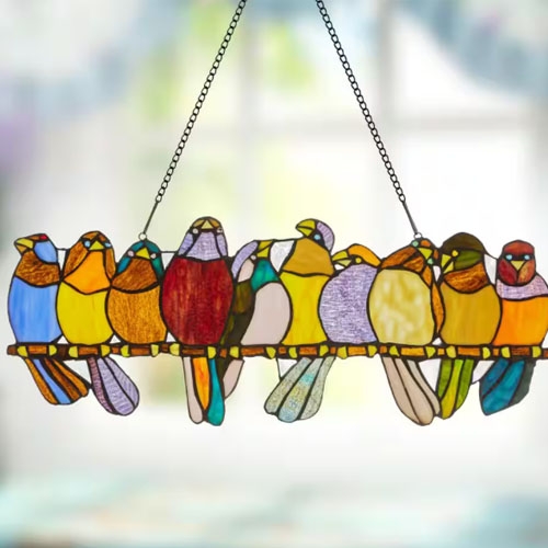 A stained glass suncatcher featuring a row of colorful birds on a perch.