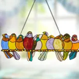 A stained glass suncatcher featuring a row of colorful birds on a perch.