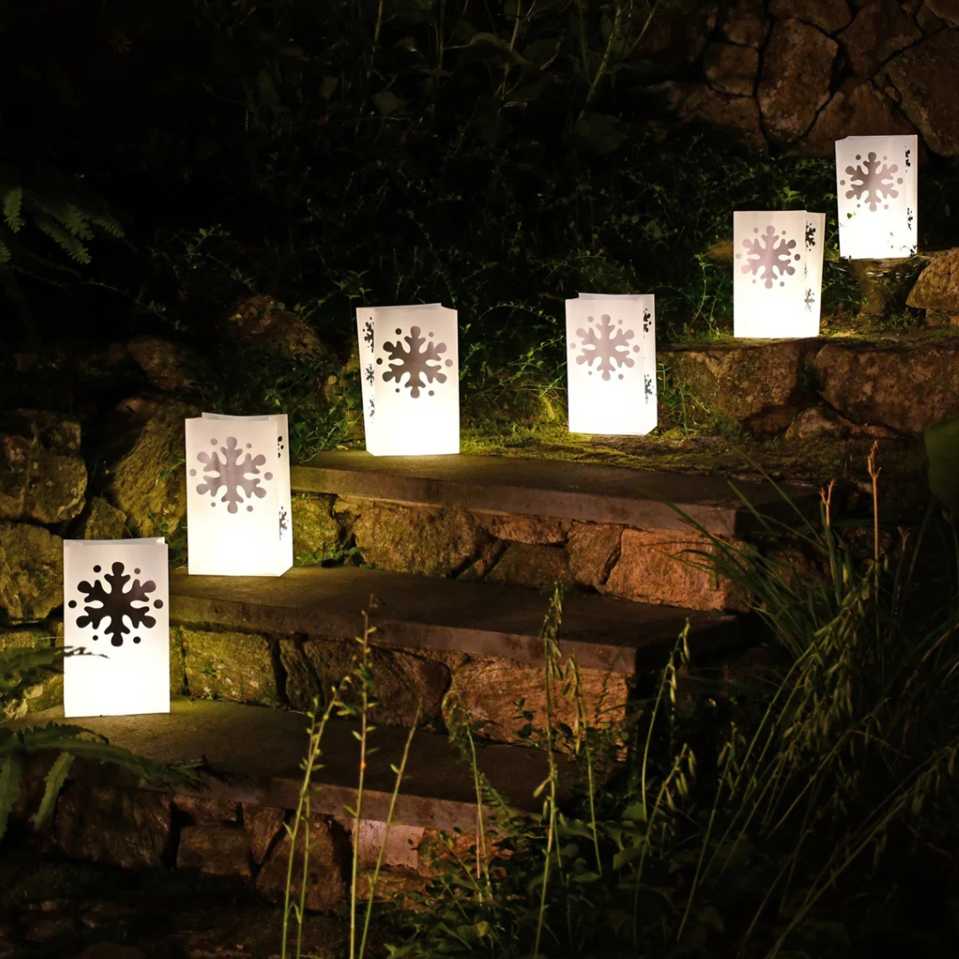 Luminaria bags with snowflake cutouts are placed along stone steps for outdoor lighting.