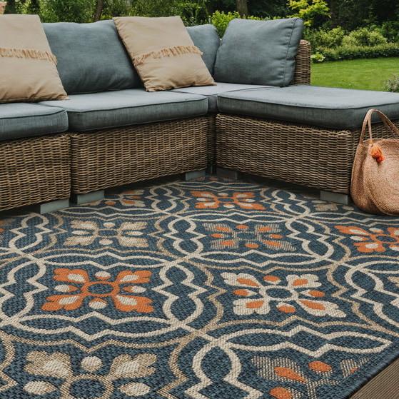 Outdoor sectional wicker sofa with cushions and a patterned area rug.