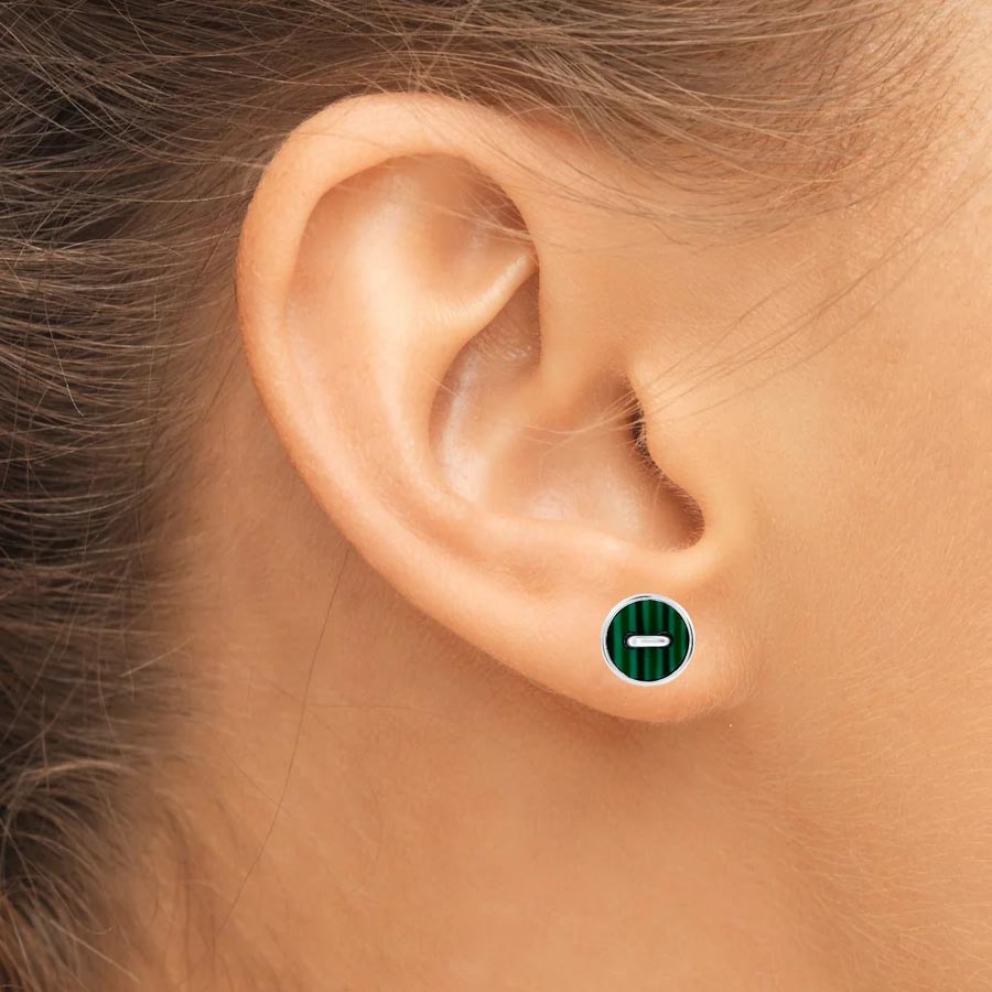 A close-up of a person's ear showcasing a stud earring with a green circular design and a horizontal line in the center.