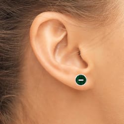 A close-up of a person's ear showcasing a stud earring with a green circular design and a horizontal line in the center.