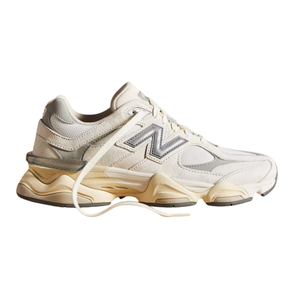 A cream-colored New Balance sneaker with a silver \“N\“ logo and beige sole, featuring a chunky design and a mesh and suede upper.