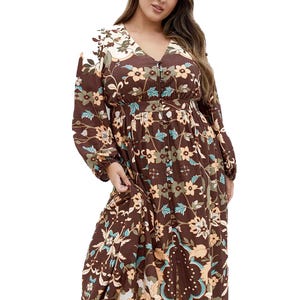 A woman wears a brown floral long-sleeve maxi dress featuring a V-neckline and button details.