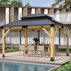 A wooden gazebo with a black metal roof is set up on a poolside patio, featuring a dining table and chairs underneath.