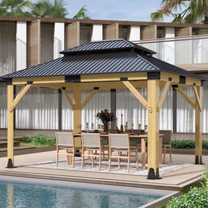 A wooden gazebo with a black metal roof is set up on a poolside patio, featuring a dining table and chairs underneath.