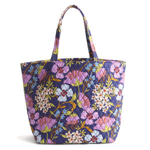 A quilted tote bag with a colorful floral pattern featuring pink, blue, and white flowers on a dark background.