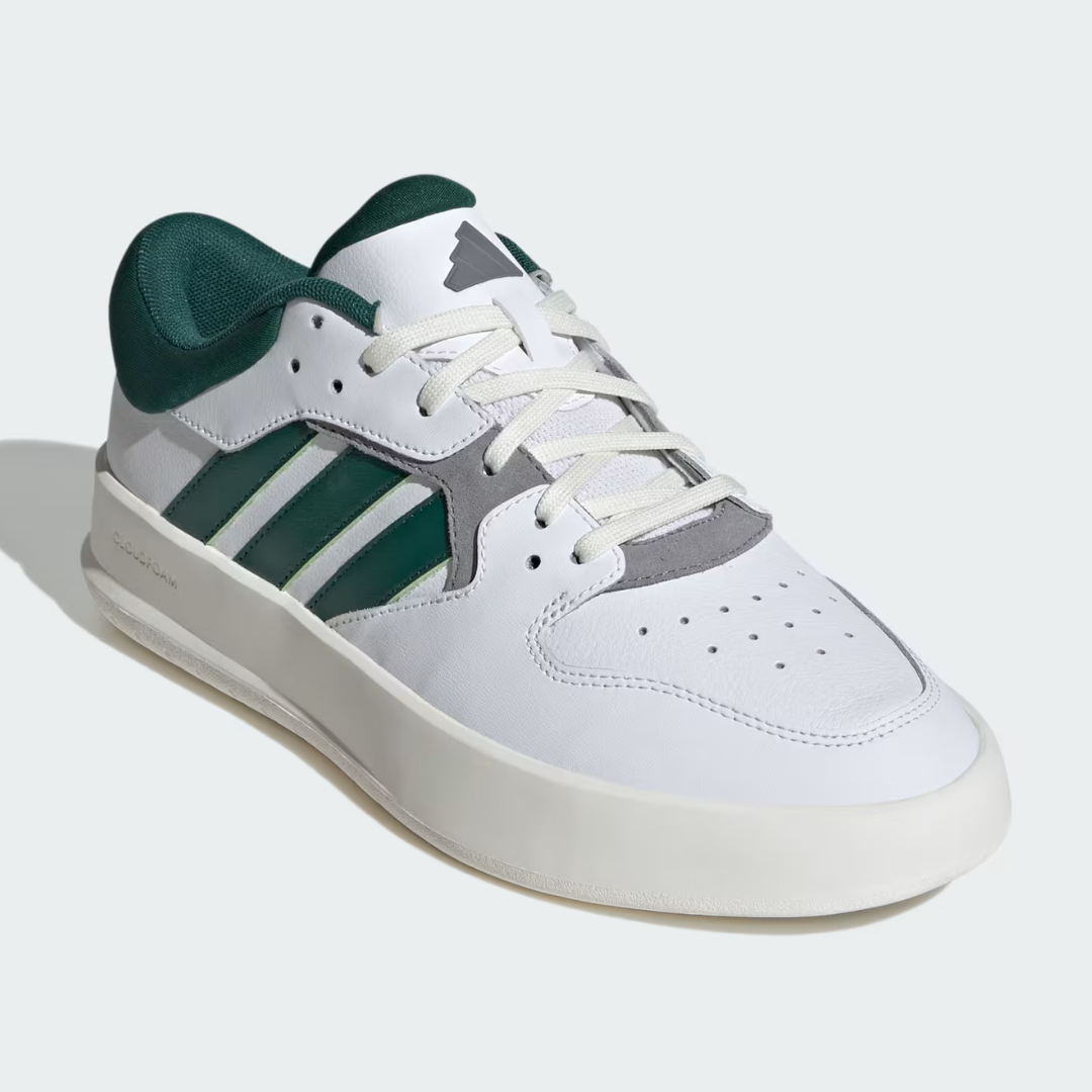 White leather Adidas sneakers with dark green stripes and heel, including a grey suede toe cap and off-white sole.