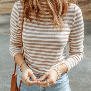 Striped long-sleeve top, pendant necklace, layered bracelets, rings, and blue jeans.