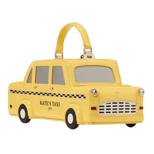A playful Kate Spade handbag designed as a yellow 3D taxi with a handle on top. Features include black and white checkered detailing and the text \“KATE'S TAXI 1993\“ on the side.