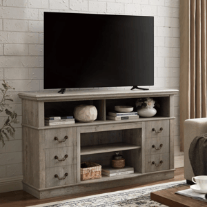 A wooden TV stand with drawers and shelves holds a flat-screen TV. Decorations, books, and a woven basket are arranged on the shelves, complemented by a cream curtain and a patterned rug.