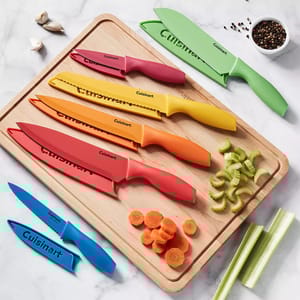 A set of colorful Cuisinart knives with matching blade covers on a wooden cutting board, surrounded by chopped carrots and celery.
