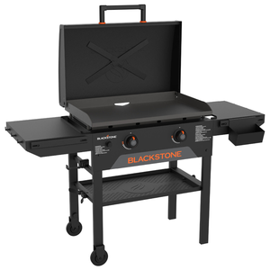 The Blackstone 28\“ Griddle with Hood features a flat top cooking surface with two burners, side shelves for extra storage, and a bottom shelf for support. It includes a hood for heat retention and wheels for mobility.